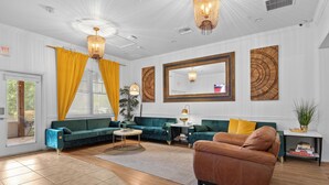 A spacious living room with a green sofa, a brown leather chair, and a large mirror. - Banana Leaf Villa (Orlando)