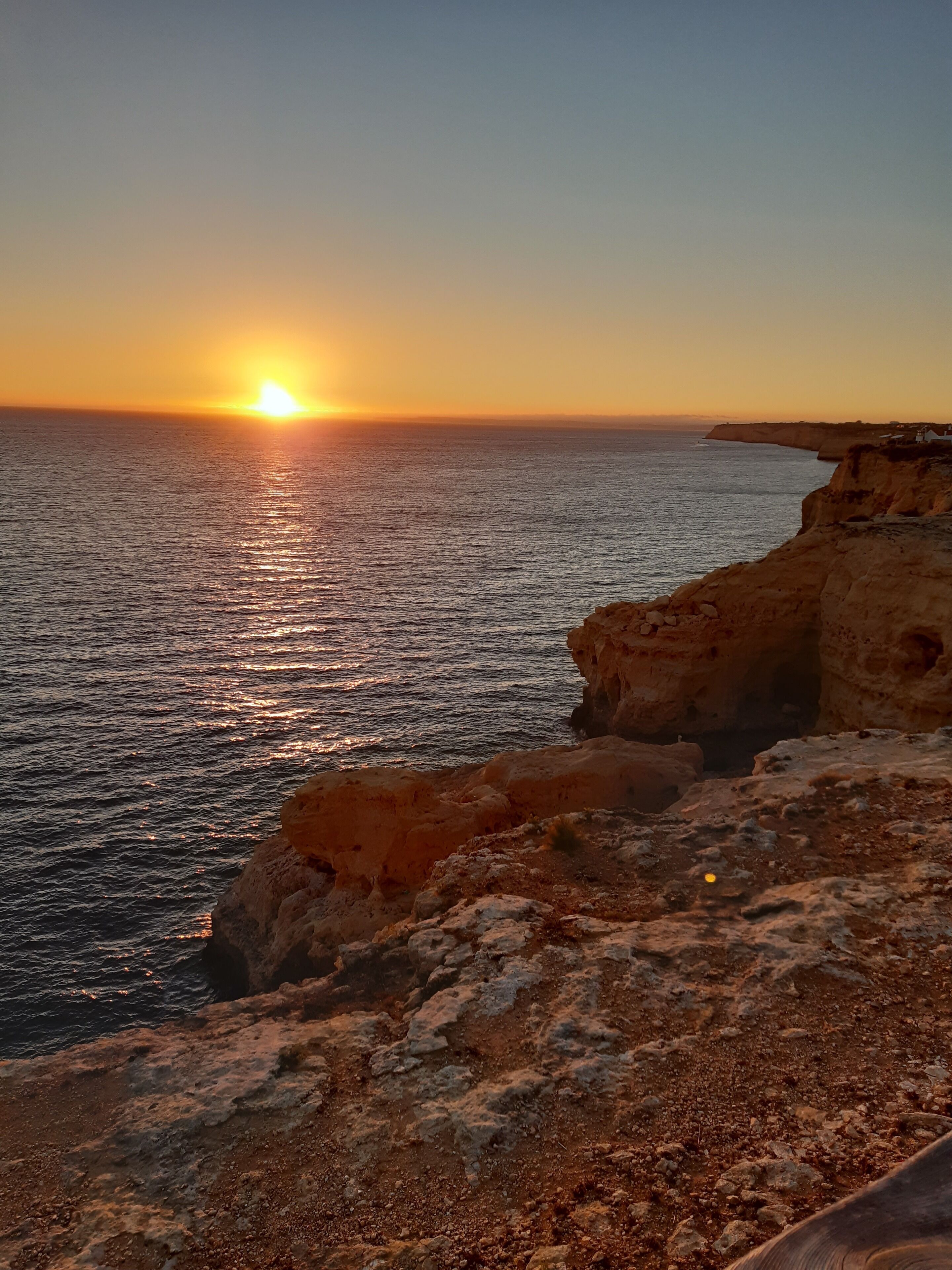 Ein Küsten-Sonnenuntergang mit felsigem Gelände und Klippen.
