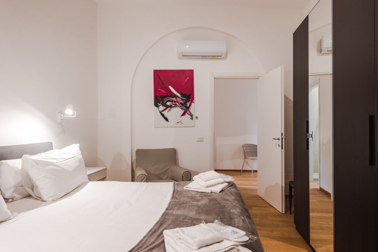 Habitación de hotel moderna con una cama grande, una silla, un escritorio y un armario.