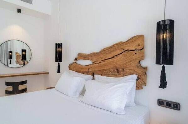 A modern bedroom with a large bed, a round mirror, and two wall-mounted lights.