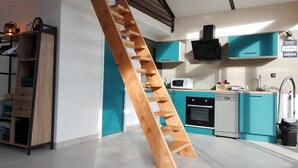 A modern kitchen with teal cabinets, a wooden ladder, and a microwave. - Welcome to Casa Beausite (Gap)