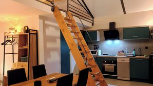 A modern kitchen with a wooden staircase leading to a loft bedroom. - Welcome to Casa Beausite (Gap)