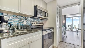 A modern kitchen with white cabinets, a stainless steel microwave, an oven, and a coffee maker. - Camelot Getaway Renovated in 2025 (Myrtle Beach)