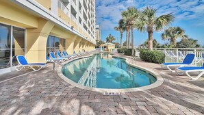 A pool area with lounge chairs and a building with balconies. - Camelot Getaway Renovated in 2025 (Myrtle Beach)