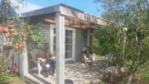 A rustic wooden house with a porch, a dog, and a tree with fruit.