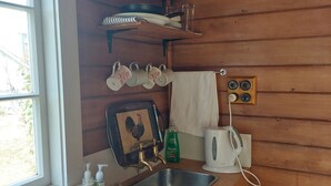 A kitchen with wooden walls, a stainless steel sink, and various kitchen items on shelves.