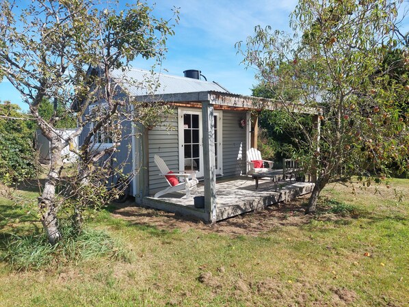 A small, single-story house with a porch and a covered outdoor seating area.