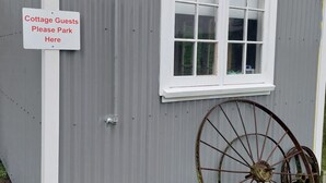 A grey cottage with a sign for 'Cottage Guests Please Park Here'.