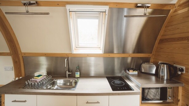 Pieni, käytännöllinen keittiö, jossa on pesuallas, liesi ja leivänpaahdin.
