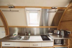 Een kleine keuken met een spoelbak, fornuis en broodrooster.