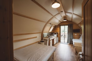 Een compacte, goed verlichte kamer met een bed, een klein keukentje en een eethoek.