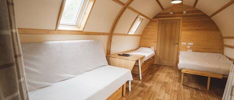 Una habitación acogedora y compacta con techo de madera, un sofá, una cama y un escritorio pequeño con una silla.