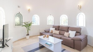A modern living room with a beige sofa, a white coffee table, and a potted plant.