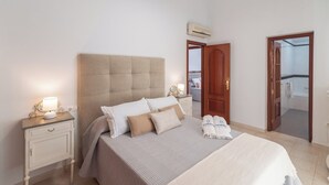 A neatly arranged bedroom with a large bed, bedside tables, a wardrobe, and an air conditioning unit.