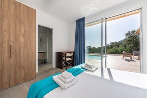 Une chambre moderne avec un grand lit, une armoire en bois, un bureau et une vue sur une piscine et un espace de détente extérieur.
