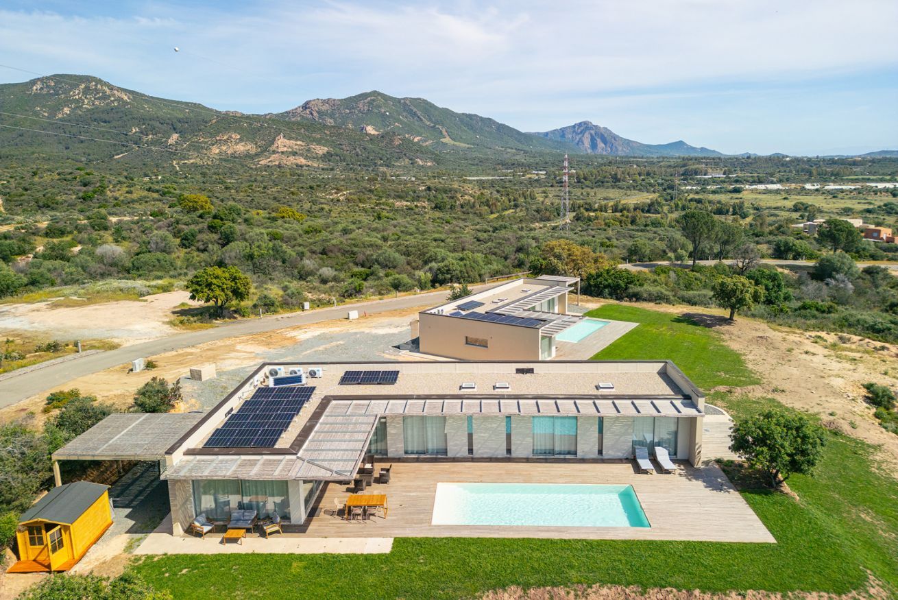 Una casa moderna con piscina, pannelli solari e vista sulle montagne.