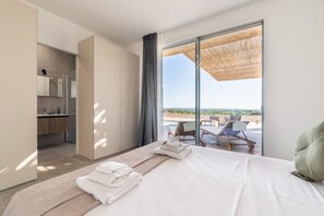 Une chambre d’hôtel moderne dotée d’un grand lit, d’une salle de bain et d’un balcon avec vue sur la plage.