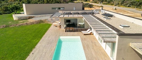 A modern house with a swimming pool, solar panels, and a patio area.