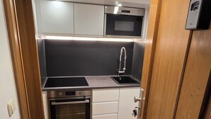 Uma cozinha compacta com forno embutido, micro-ondas e pia.