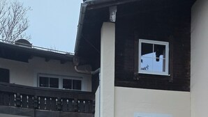 Um edifício de dois andares com entrada coberta, uma pequena árvore e uma luz exterior acesa.