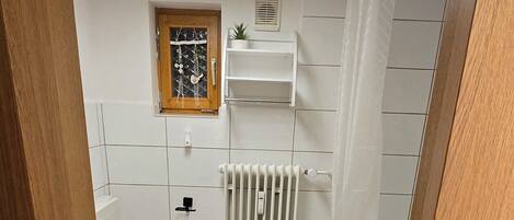 Kylpyhuone, jossa on wc, patteri ja suihkutila.