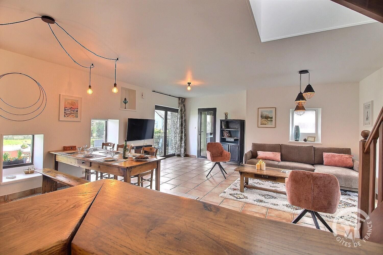 A spacious living area with a wooden dining table, a sofa, and a TV.