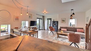A spacious living area with a wooden dining table, a sofa, and a TV. - Tabata - PLOURHAN - Gîte (PLOURHAN)