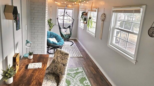 A cozy room with a wooden floor, a hanging chair, a dining table, and a green ceiling. - Updated 4-bedroom house with relaxing sunroom; minutes from downtown Raleigh. (Garner)
