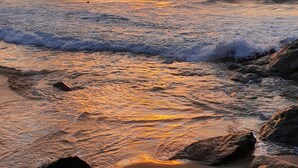 A beach with waves and rocks at sunset. - Aldea Bamboo Village (San Francisco)
