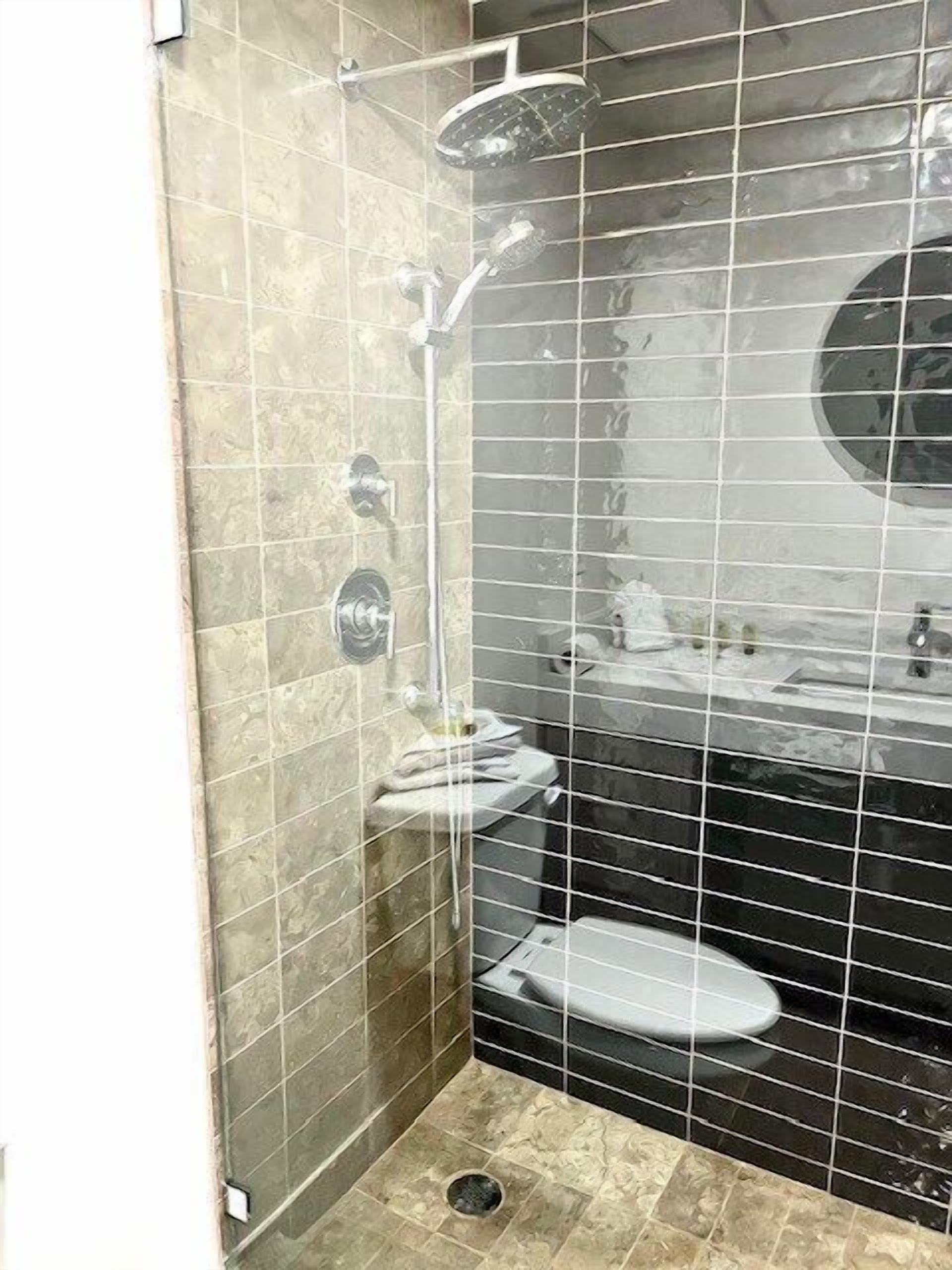 Une salle de bain avec douche, toilettes et lavabo.