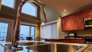 A modern kitchen with a stainless steel sink, wooden cabinets, and a built-in microwave. - Pilley's Perch - Entire home in Pilley's Island, Canada. Beautiful Ocean View (Pilley's Island)