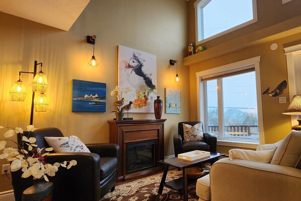 A cozy living room with a fireplace, comfortable seating, and artwork on the walls.