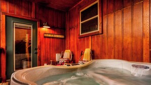 Interior de madera con un jacuzzi, dos sillones y un cartel que dice 'HOTUB'.