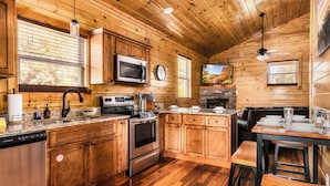 Una cocina de estilo cabaña de madera con lavavajillas, estufa, microondas y comedor.