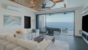 A modern living room with a sofa set, a coffee table, and a view of the ocean through large glass doors. - Casa Picos Palace with swimming pool and panoramic ocean view in Huatulco Bays (Santa María Huatulco)