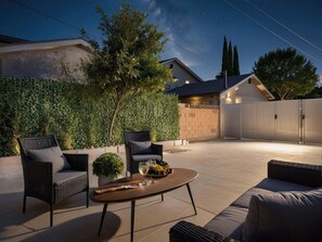 An outdoor patio with a round table, two chairs, and a sofa.