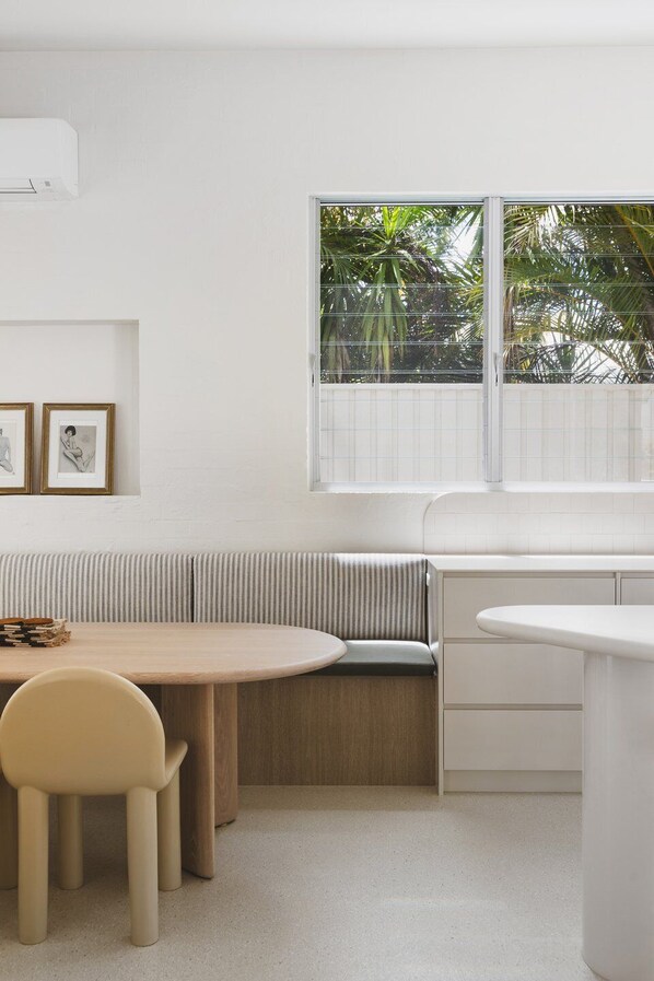 Una cocina moderna con una banca empotrada, una mesa de comedor con sillas y un ventanal con vistas a zonas verdes.