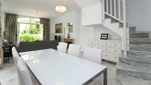 Een moderne woonkamer met een eettafel, bank en trap.