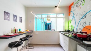Een moderne keuken met barstoelen, een raam en een muur vol tekeningen en tekst.