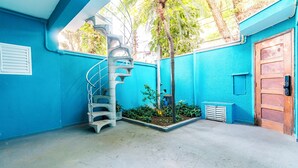 Een kamer met blauwe wanden, een spiltrap, een houten deur en een kleine tuin.