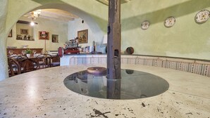 Ein Essbereich mit einem runden Glastisch, Holzstühlen und einer zentralen Säule.