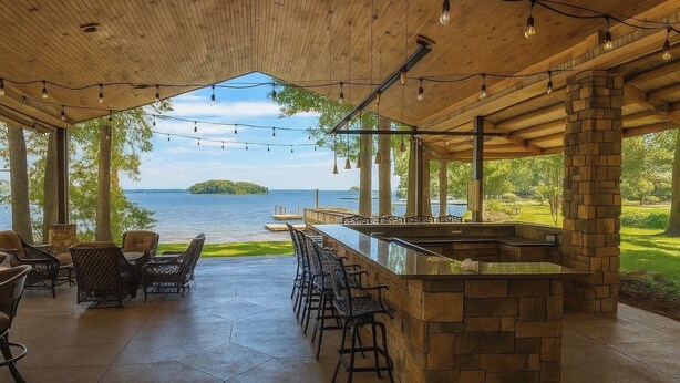 Un patio al aire libre con barra de piedra y asientos, con vista a una masa de agua.