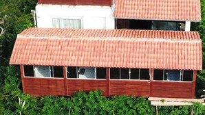 Una casa de varios pisos con techo de paja y un panel solar.
