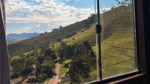 Vista a través de una ventana de un paisaje montañoso con campos en terrazas y cielo despejado.