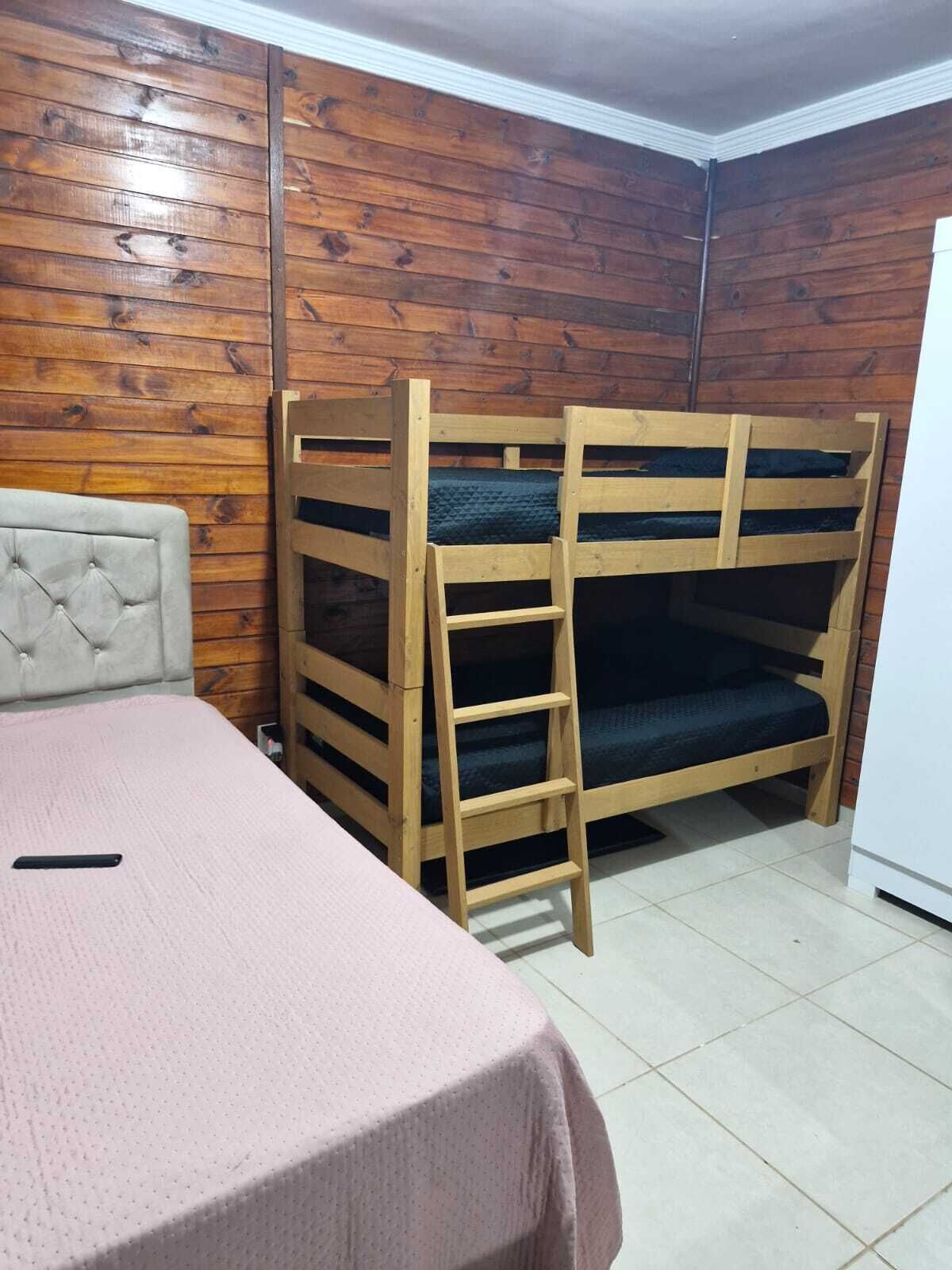 Uma cama de solteiro com escada, uma cama individual com cabeceira e piso revestido de azulejos.