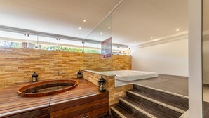Un baño moderno con tocador de madera, una bañera independiente y una pared de piedra.