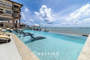 Zwembad van een resort met ligbedden en uitzicht op zee.