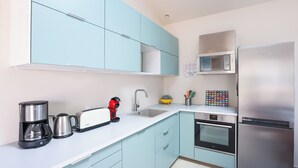 A modern kitchen with light blue cabinets, a stainless steel refrigerator, a microwave, a coffee maker, and a toaster. - Maison Fantasio - Welkeys (Dolus-d'Oléron)