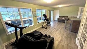 A home gym with exercise equipment, a couch, and a dining area. - Forget your worries in this spacious and serene space with a beautiful lake view (Milton)