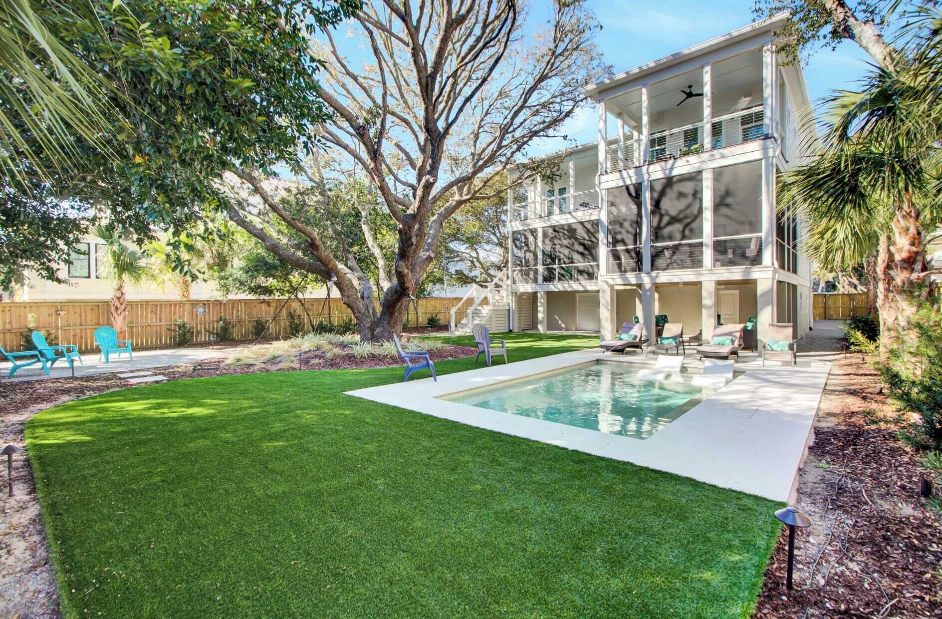 A two-story house with a swimming pool, a well-maintained lawn, and outdoor seating.